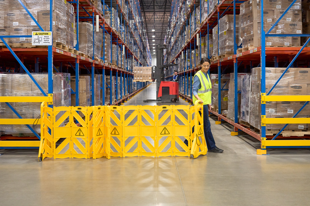 Female Warehouse Staff holding a 4m Mobile Barrier