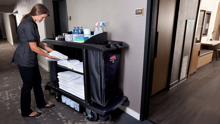 A housekeeper organising cleaning equipment on Rubbermaid's Executive Traditional Compact Housekeeping Cart