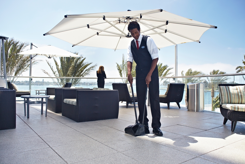 A hotel staff cleaning the rooftop lounge using an Executive Series™ Lobby Pro® Dustpan With Cover