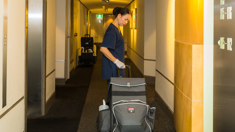 A housekeeper pulling a Rubbermaid Executive Quick Cart Caddy