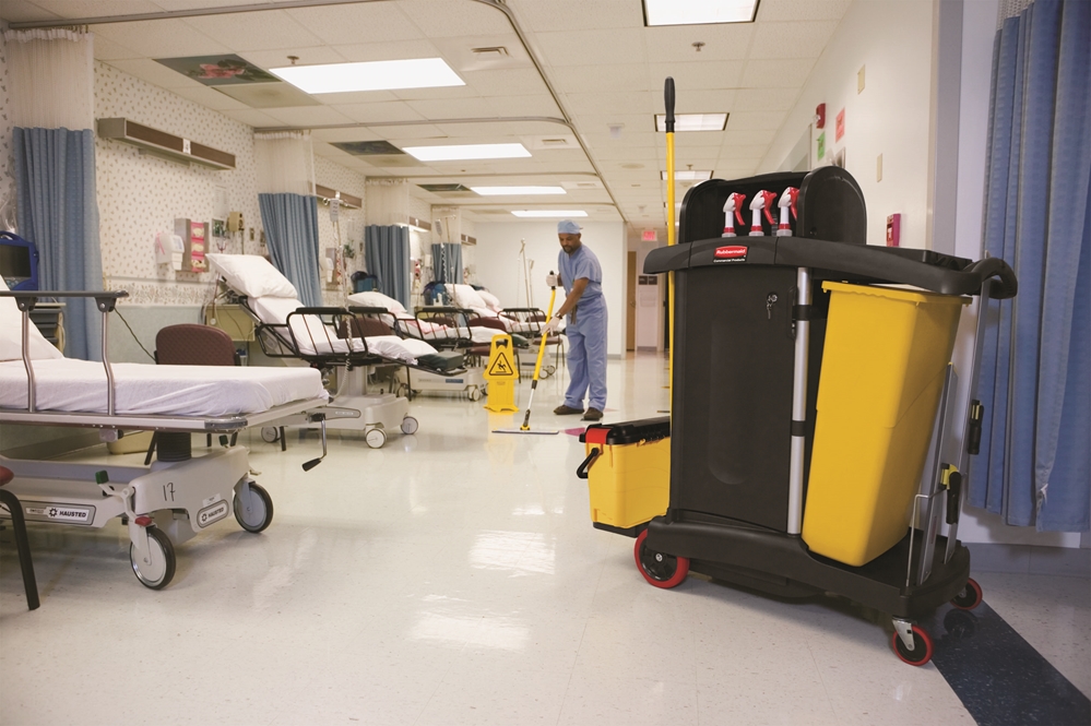 A hospital personel cleaning the ward room with the HYGEN™ PUlSE™ Microfibre Mop Kit, Rubbermaid Commercial High Security Cleaning Cart and the "Caution Wet Floor" Sign
