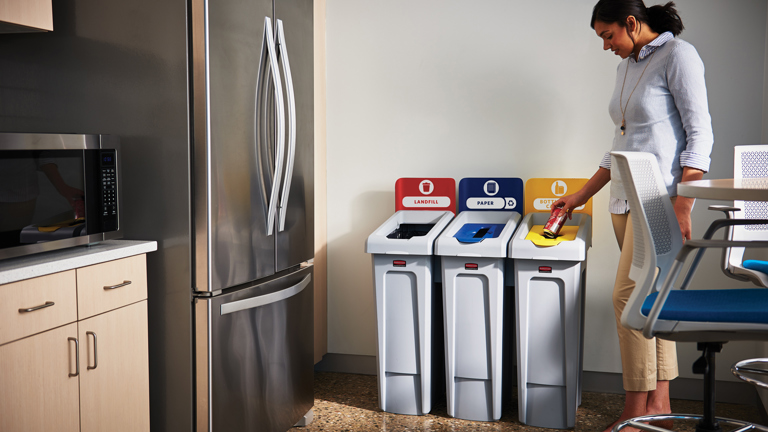 An office worker throwing a trash to the Rubbermaid Commercial Slim Jim Recycling Station