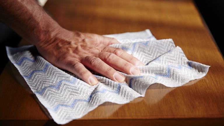 A person cleaning a wooden table using a HYGEN™ Disposable Microfiber Cloth
