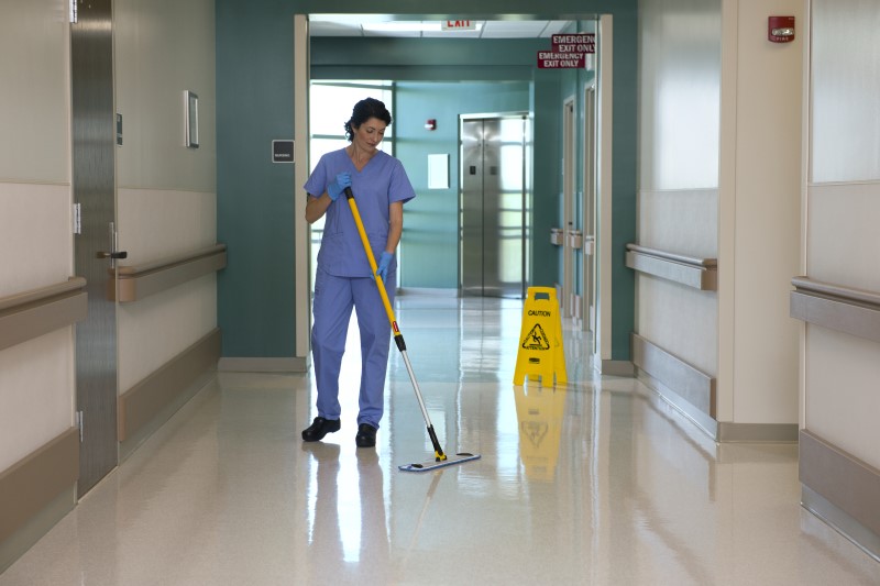 A hospital worker cleaning the floor using Rubbermaid HYGEN Pulse Microfiber Mop Kit
