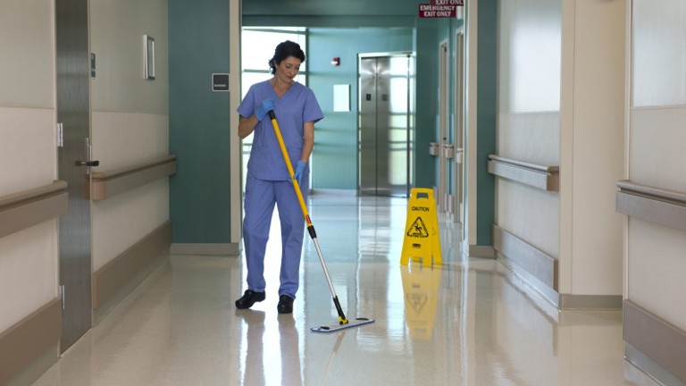 A hospital worker cleaning the floor using Rubbermaid HYGEN Pulse Microfiber Mop Kit